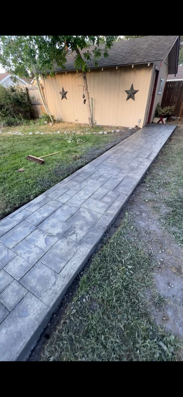 Stamped concrete walkway alongside a backyard shed